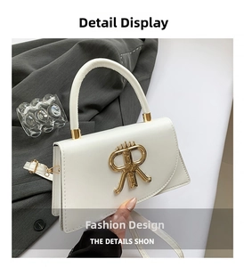 Detail of white crossbody bag featuring a golden R-letter buckle and detachable strap