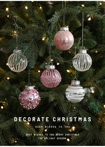Close-up of pink and white textured Christmas ornaments on an illuminated tree