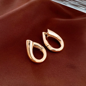 Close-up of polished gold geometric drop earrings with smooth metallic finish