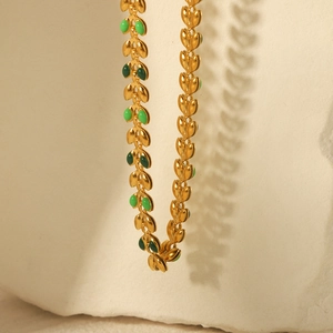 Gold-plated titanium steel olive leaf necklace with green enamel drops on textured stone