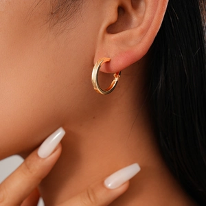 Close-up of minimalist gold circular hoop earrings worn by a model for a sleek aesthetic