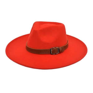 Détail d'un chapeau fedora rouge vif avec ceinture en cuir marron et boucle en métal