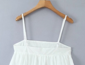 Detail of white spaghetti strap top showing smooth fabric texture and thin straps