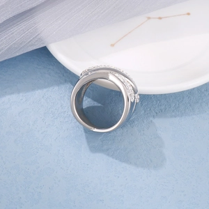 Exaggerated silver stainless steel crisscross ring with micro-pave crystals on blue texture