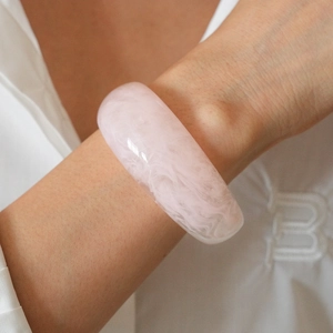 Macro shot of wide pink resin bangle with marble texture on a model's wrist