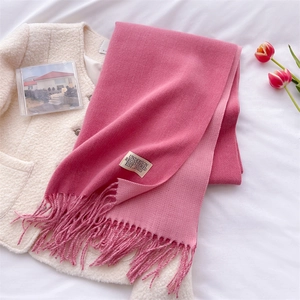 Detailed macro shot of pink gradient cashmere scarf with fringe on a white coat