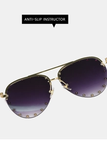 Detail of pilot sunglasses with purple gradient lenses and gold beaded metal frame