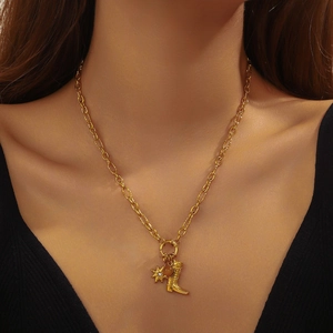 Gold plated beaded necklace with star and boot charms on model's neck