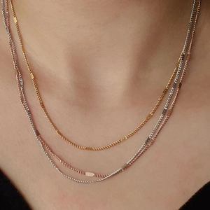 Detailed close-up of gold, rose gold and silver minimalist thin necklaces layered on neck