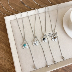 Detail of four flower pendant necklaces on silver snake chains with colorful beads