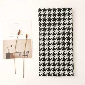 Detailed view of black and white houndstooth scarf flat lay with minimalist decor