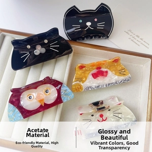 Détail de pinces à cheveux chat en acétate de couleurs variées sur plateau présentoir