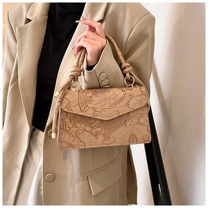 Detail of embossed koi fish and lotus pattern on beige PU leather crossbody bag