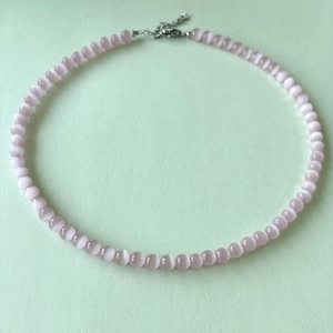 Detail of pink cat-eye stone beaded necklace with silver lobster clasp and extension