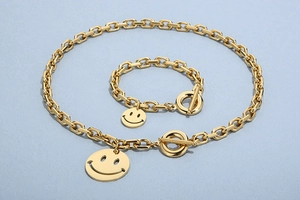Detail of golden smile face pendant set with rectangular link chain and OT toggle clasp