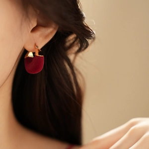Close-up of elegant burgundy velvet U-shaped earring with gold plating worn by a model
