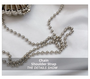 Detail of silver shell-shaped metal evening bag with glossy beaded chain strap