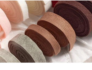Close-up of rolled wool felt ribbons in pink, brown, and grey for DIY Christmas crafts
