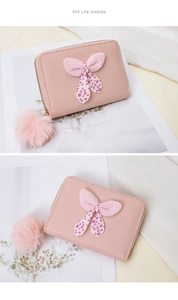 Detailed close-up of pink leather coin purse with polka dot bow and plush ball charm