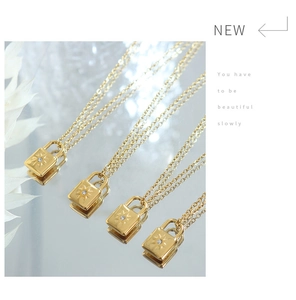 Detailed view of gold padlock pendant necklace with sunburst texture and zircon on mirror