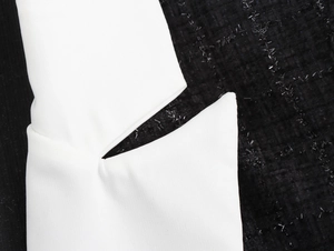Détail du design contrasté montrant le col blanc et la texture en tweed noir du manteau