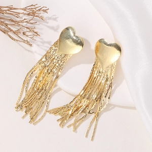 Detailed close-up of gold heart fringe earrings with long metallic tassel chains