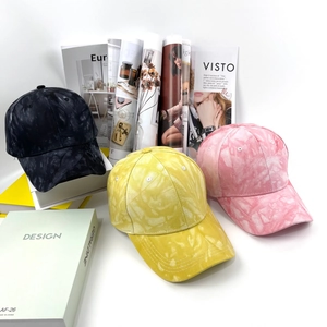 Dettaglio del cappello da baseball tie-dye con motivi marmorizzati neri, gialli e rosa