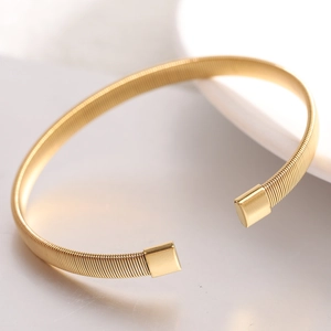 Detail of 6mm gold stainless steel spring cuff bracelet with polished square end caps