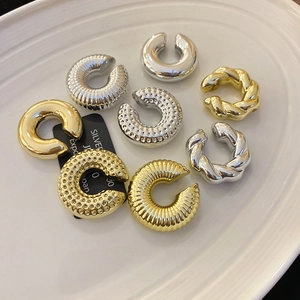 Gros plan de boucles d'oreilles ear cuffs dorées et argentées aux finitions texturées