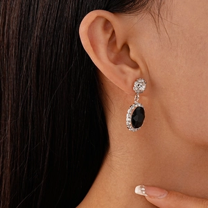 Gros plan de boucles d'oreilles argentées avec pierre ovale noire et zircons brillants