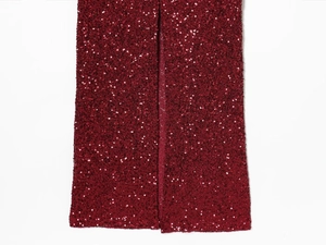 Detailed close-up of dark red sequin dress featuring a high side slit and fine craftsmanship