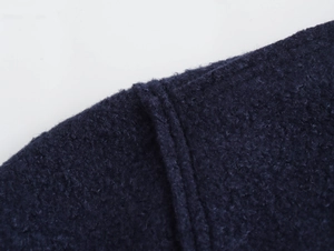 Gros plan sur la texture bouclée bleu marine et les coutures de la veste en tweed