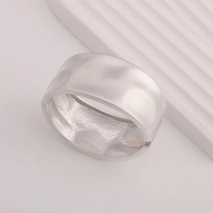 Detailed macro view of silver hammered texture on a wide minimalist metal open bangle