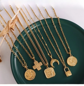 Detailed view of layered 18k gold plated stainless steel necklaces on a green plate