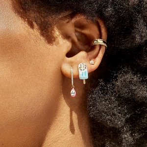 Close-up of gold hoop earrings and ear cuffs with pink drip glaze and sparkling crystals