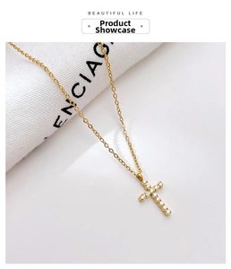 Detail of a minimalist gold cross pendant necklace with sparkling inlaid zircons