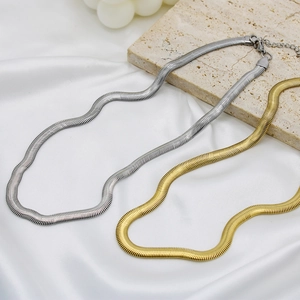 Golden and silver 6mm flat snake bone necklaces on white silk and stone background