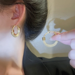 Detail showing woven texture and polished gold finish on these hollow hoop earrings