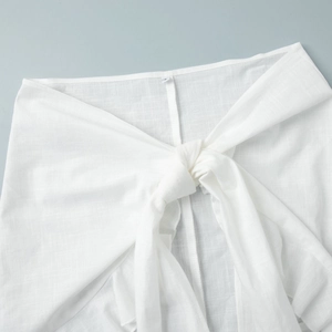Detailed view of white cotton linen shirt dress featuring waist tie knot and texture