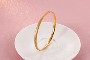 Detail of gold titanium steel bangle showing shimmering frosted finish and polished inner surface