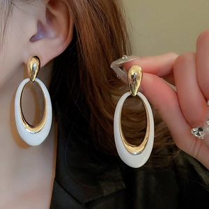 Close-up of vintage oval enamel earrings in gold and white with high-quality metal finish