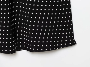 Close-up of polka dot fabric texture and hem stitching on a halter neck dress