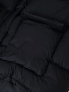 Detailed macro view of black puffer jacket showing quilted texture and premium nylon fabric