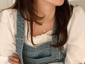 Polished silver heart pendant necklace shown on neck with chic casual outfit