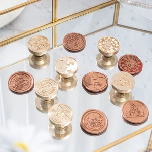 Macro detail of vintage solid brass wax seal heads with clock and animal patterns