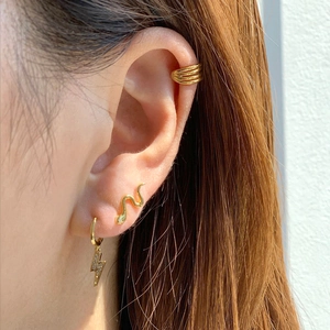 Gold snake earrings and crystal lightning stud set worn by a model in close-up shot