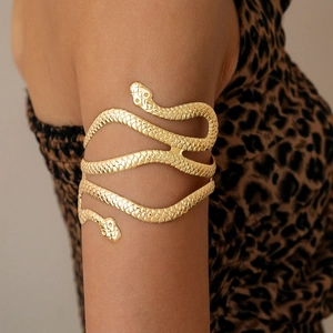 Detailed close-up of a double-headed golden snake arm cuff with textured scales on a model