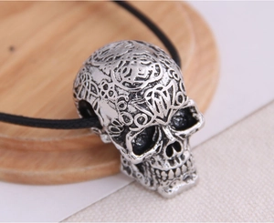 Macro shot of silver skull pendant with detailed engravings on a black rope chain