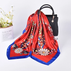 Floral print satin scarf tied to a leather handbag with red daisy pattern details