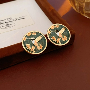 Close-up of vintage round earrings with hummingbird and flower enamel patterns